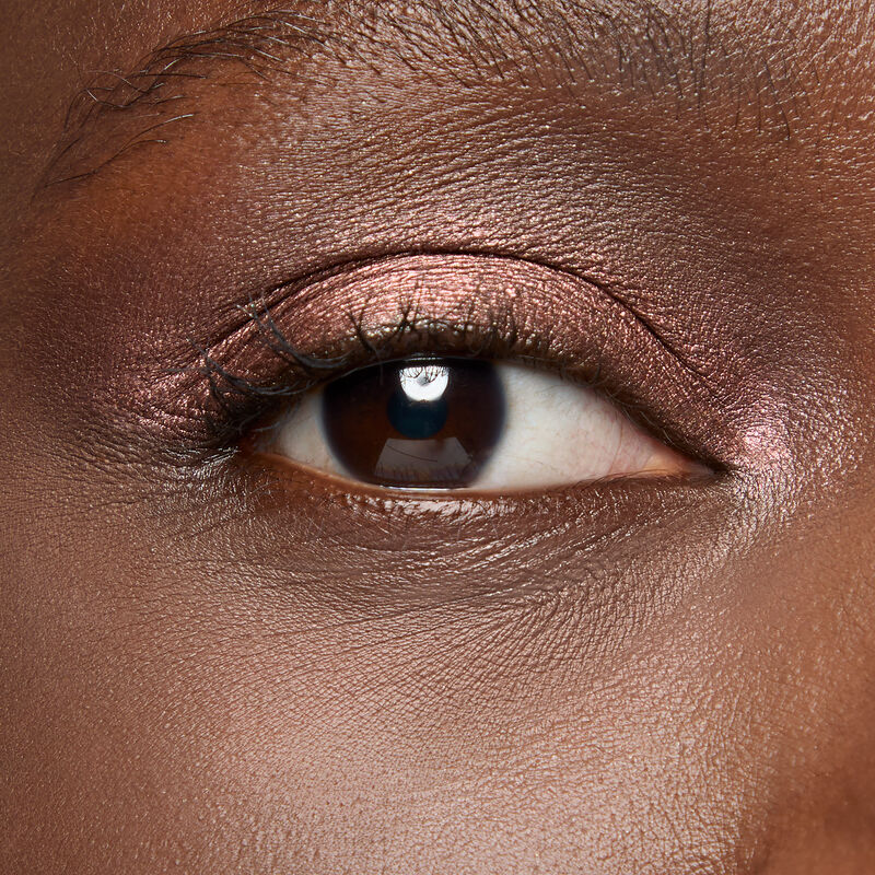 A model with a deep skin tone and brown eyes wears shade Radiant Bronze.