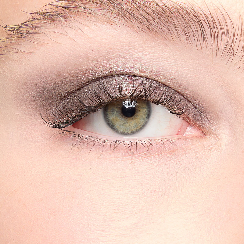 A model with a light skin tone and green eyes wears shade Midnight Galaxy