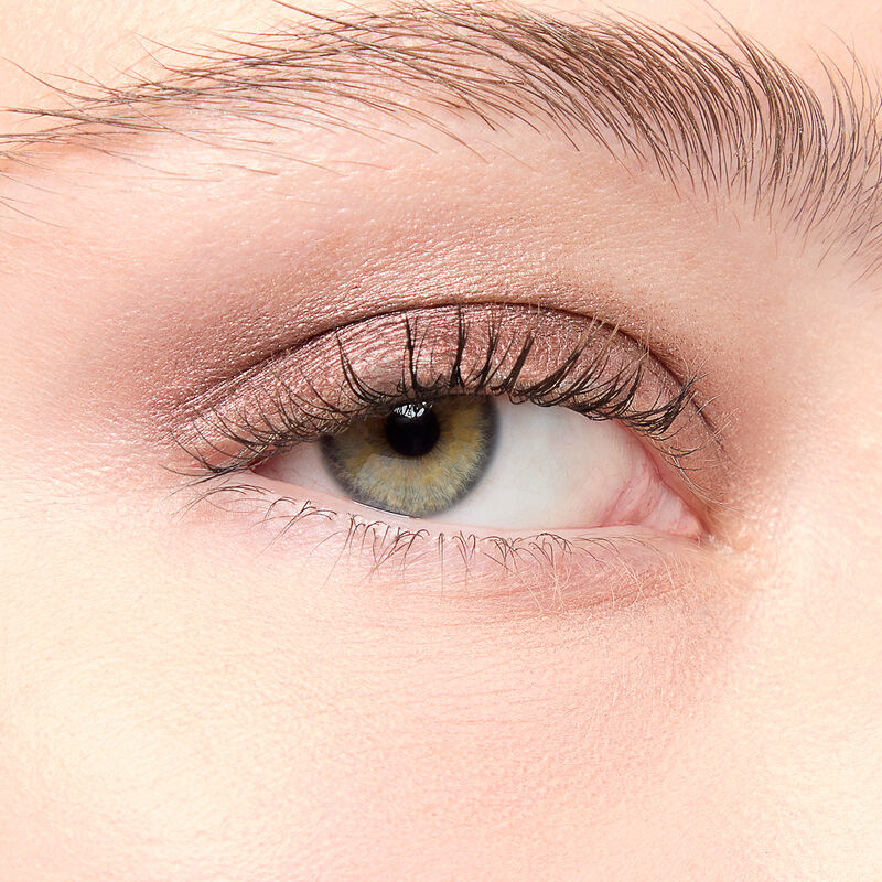 A model with a light skin tone and green eyes wears shade Radiant Bronze.