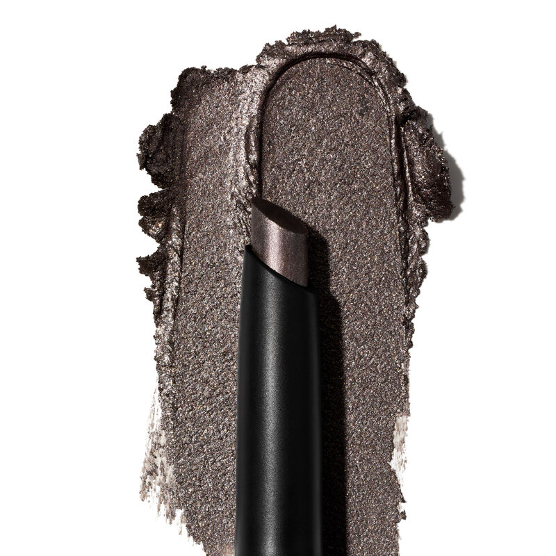 A product rub showing off the Midnight Galaxy shade finish, and texture appears on a white surface with the uncapped product in front of it.