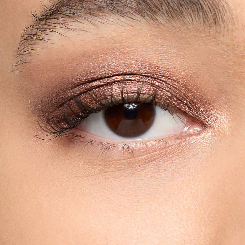 A model with a medium skin tone and brown eyes wears shade Radiant Bronze.