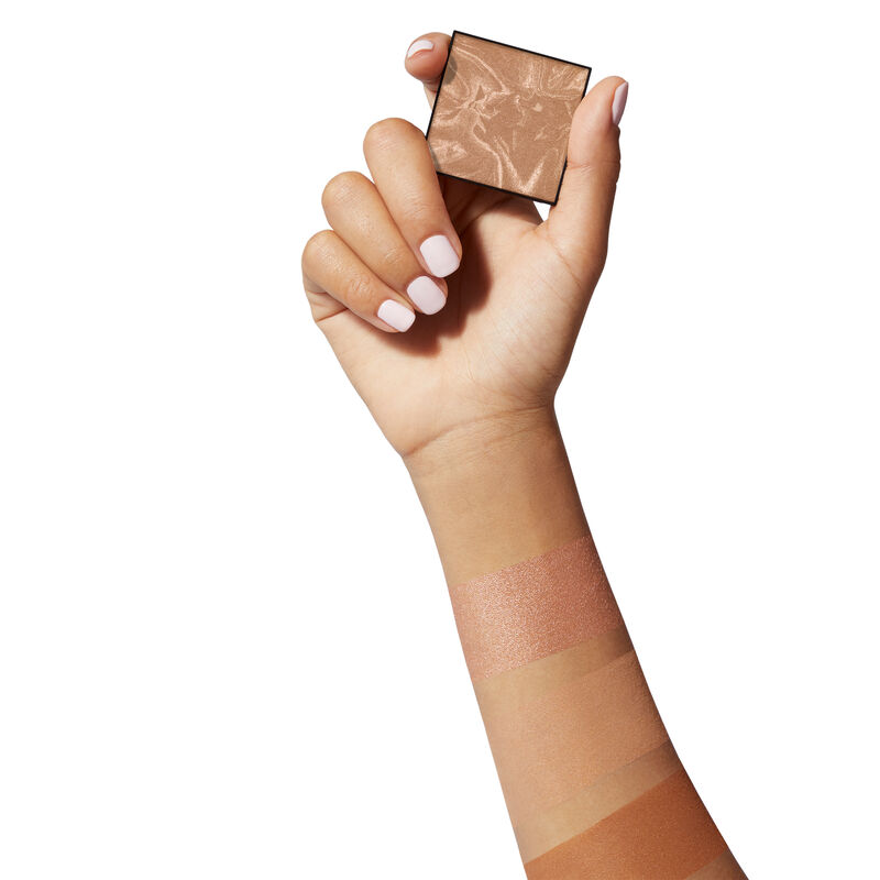 Hand mittlere Hautfarbe h&auml;lt Bronzer. Farbmuster der Bronzer auf dem Arm. 