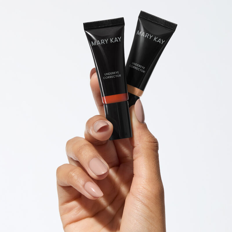 A hand holds Mary Kay&reg; Undereye Corrector in shades deep peach and light peach.
