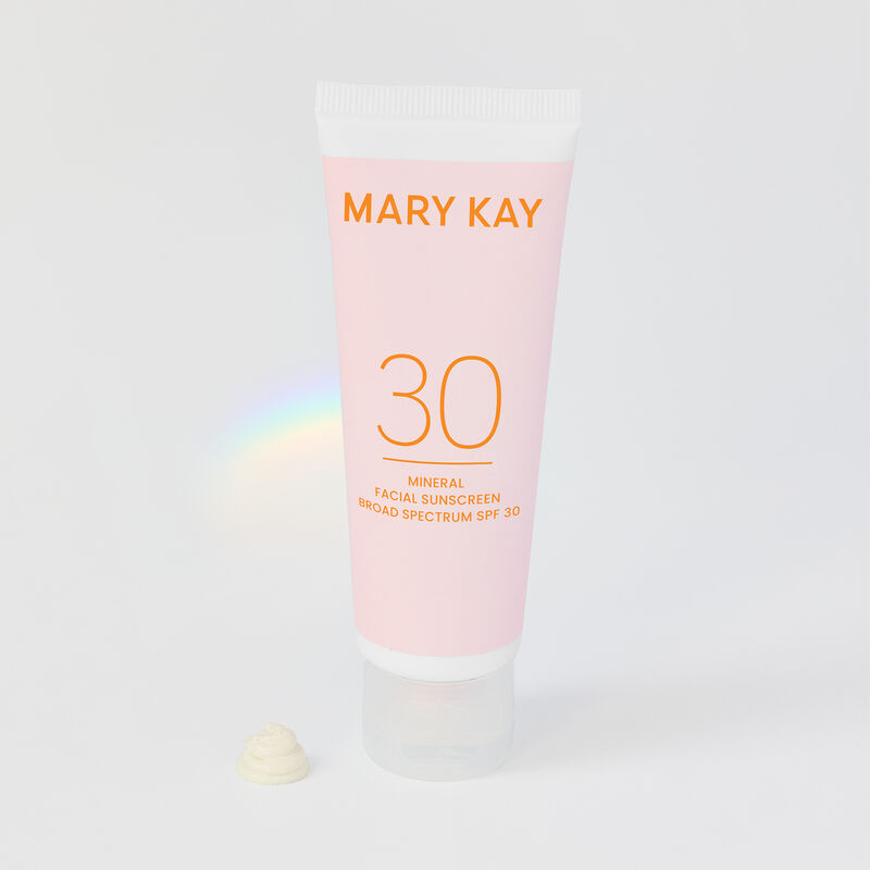 Bottle of Mary Kay Mineral Facial Sunscreen Broad Spectrum SPF 30* standing on its cap with rainbow prism in the background  image number null