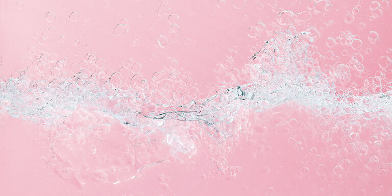 Nahaufnahme der Zwei-Phasen-Formel des &ouml;lfreien Augen-Make-up-Entferners von Mary Kay: eine transparente, hellrosa Fl&uuml;ssigkeit mit Blasen, die durch das Sch&uuml;tteln entstanden sind