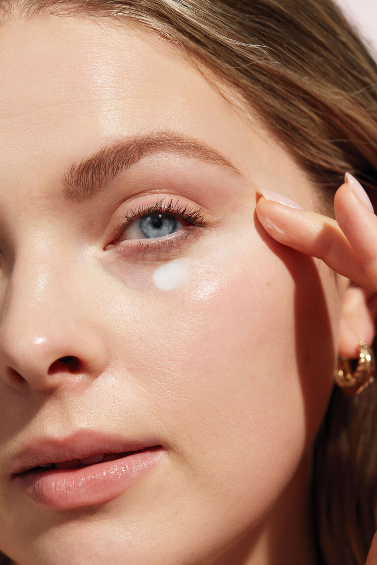 Nahaufnahme einer Frau, die Augencreme (TimeWise Eye Cream) unter dem Auge auftr&auml;gt