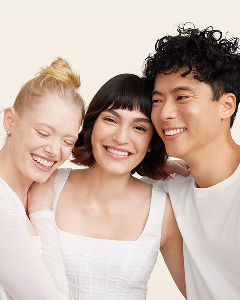 Eine Gruppe aus zwei Frauen und einem Mann, die sich umarmen und lachen.