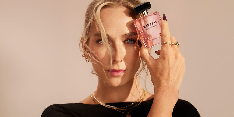 Eine Frau h&auml;lt mit einer Hand den rosa Flakon von "Confidently You" - Parfum von Mary Kay