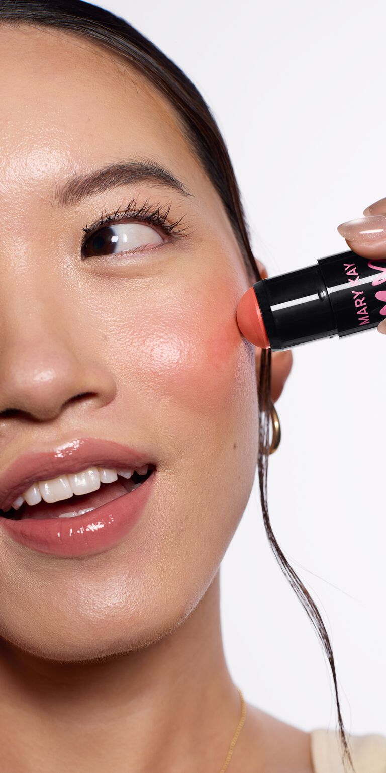 Eine Frau, die auf ihrer Wange den korallroten Blush auftr&auml;gt (Blush Stick in der Shade "Kind Spirit" von Mary Kay)