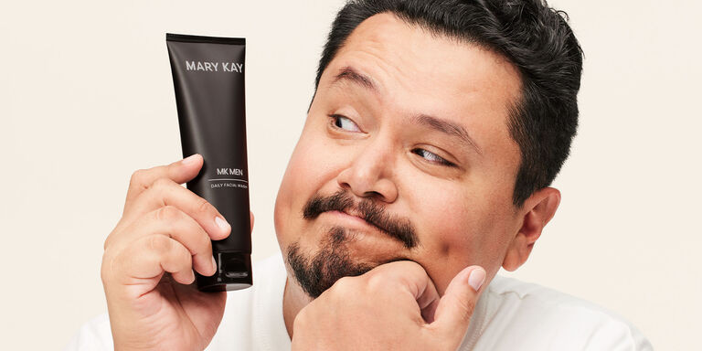 Ein Mann schaut neugierig auf eine Tube des MK Men Facial Wash, die er in der Hand h&auml;lt