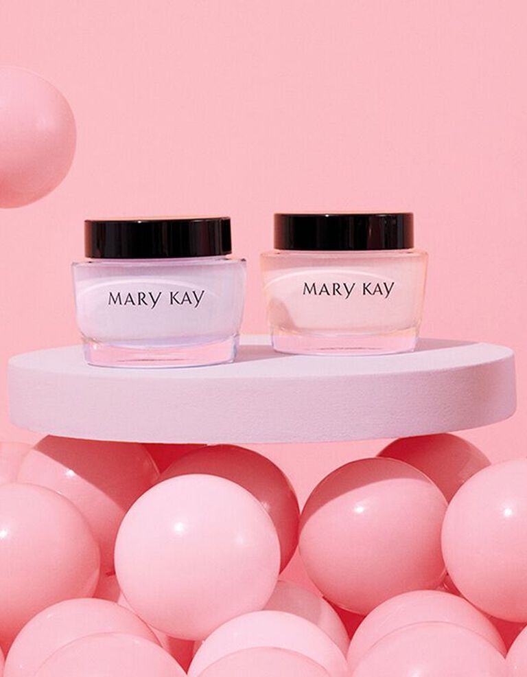 Tiegel mit Mary Kay Oil Free Hydrating Gel und Mary Kay Intense Moisturizing Cream stehen auf einem wei&szlig;en Tisch, umgeben von rosa Luftballons
