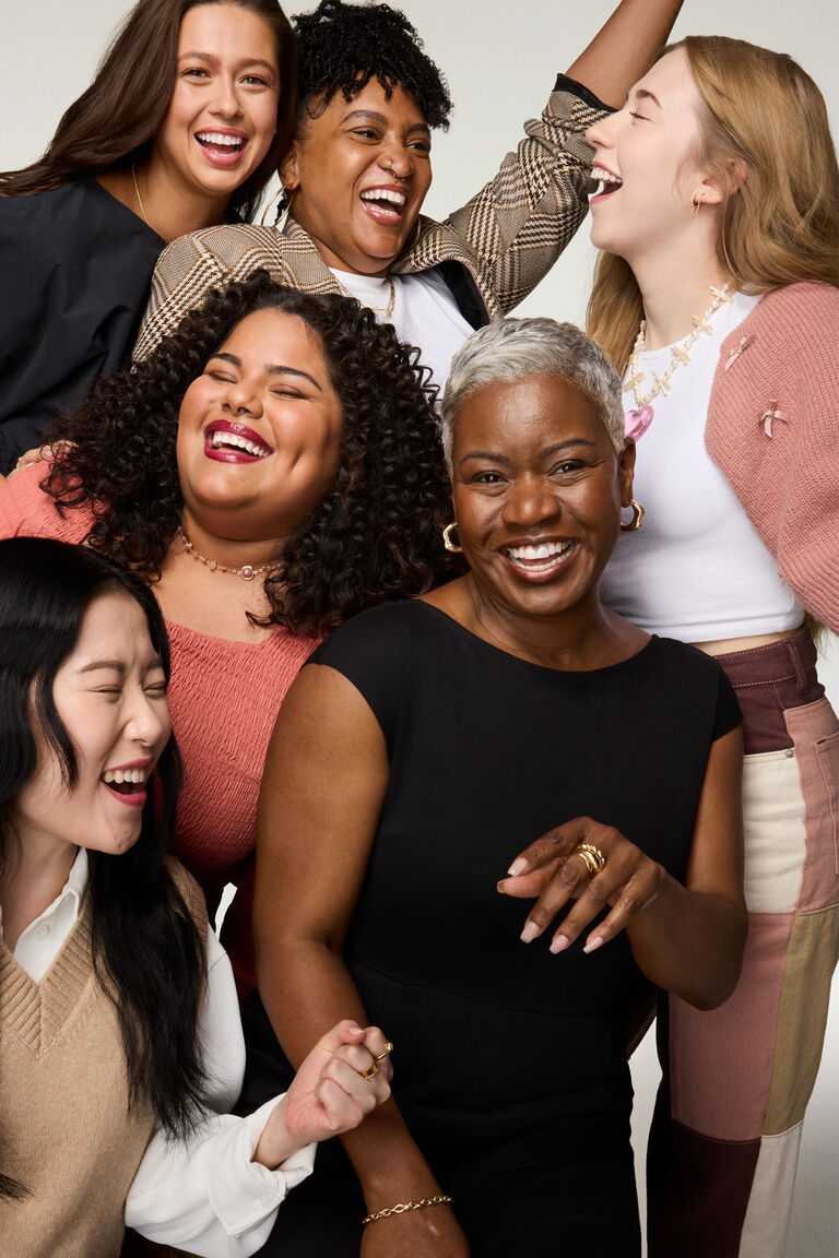 Group of diverse people wearing stylish outfits posing together against a neutral background.