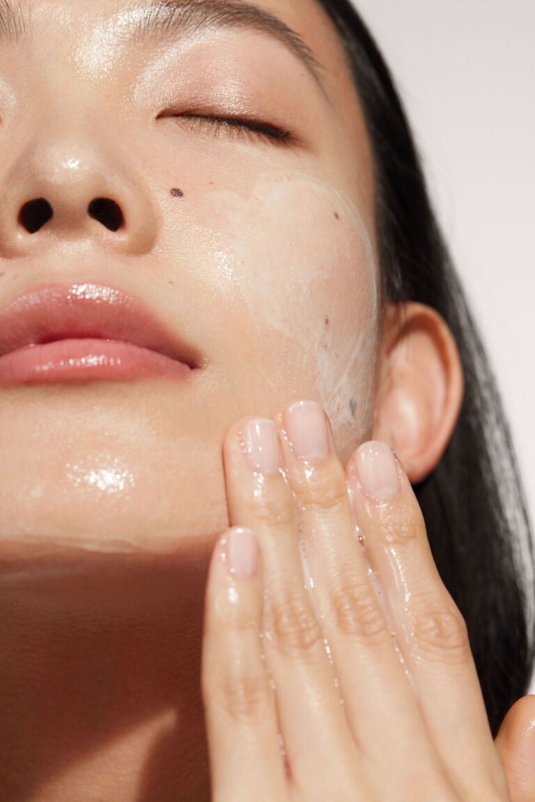 Nahaufnahme einer Frau, die mit geschlossenen Augen ihr Gesicht mit dem Cleanser aus dem TimeWise &bdquo;Wunder-Set&ldquo; von Mary Kay reinigt