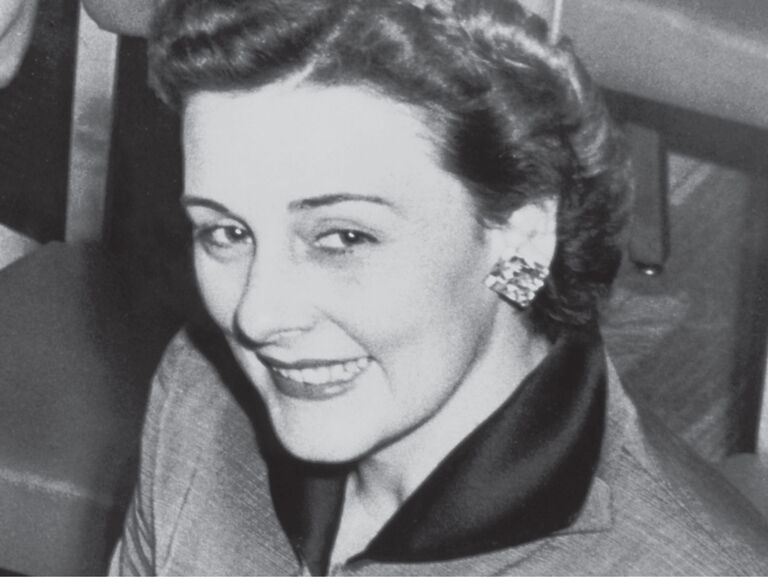 Vintage-Foto der Mary-Kay-Gr&uuml;nderin in einem eleganten Anzug und auff&auml;lligen Ohrringen.