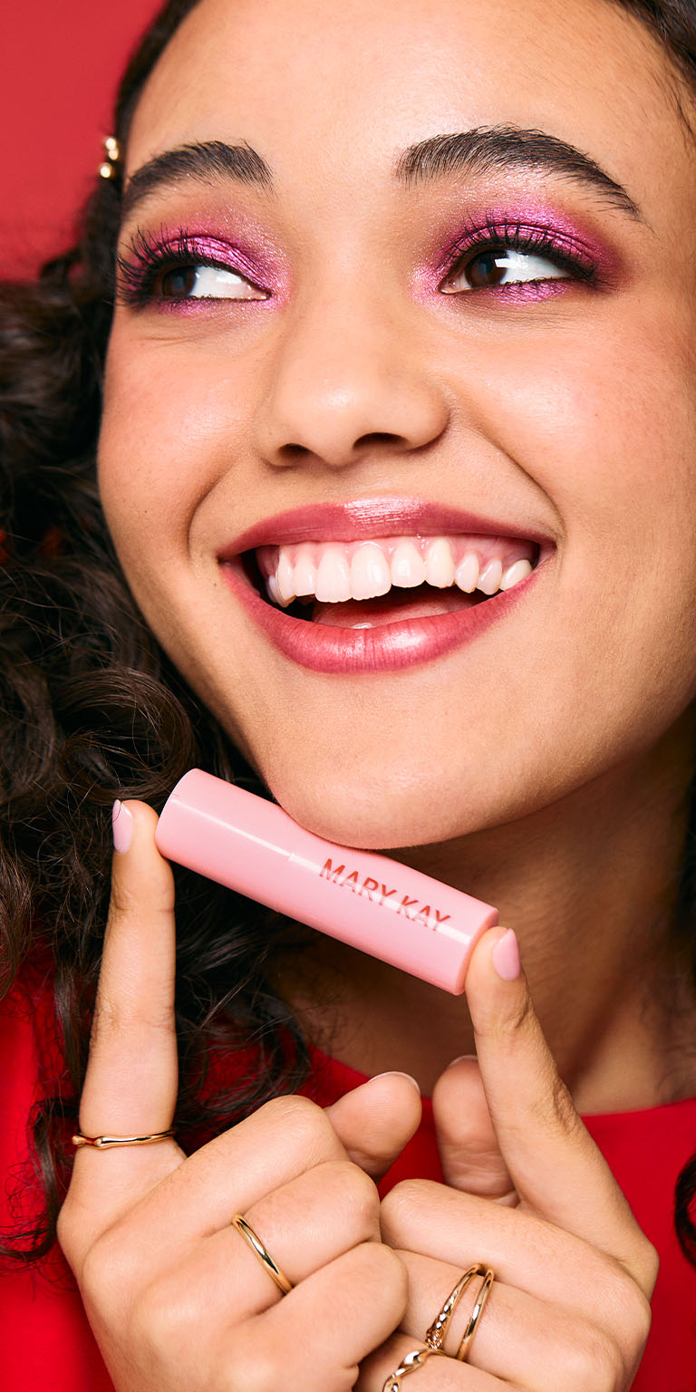 L&auml;chelndes Model mit einer Tube des limitierten Mary Kay Tinted Lip Balm in Radiant Pink in der Hand
