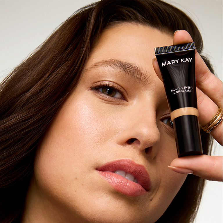 Nahaufnahme einer Frau, die eine Tube Mary Kay Multi-Benefit Concealer vor ihr Gesicht h&auml;lt