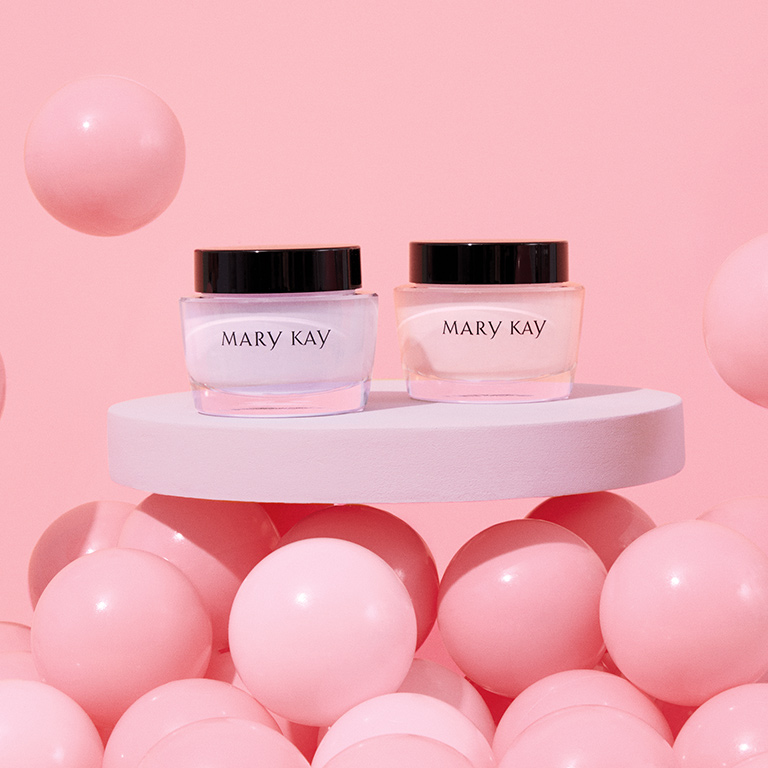 Tiegel mit Mary Kay Oil Free Hydrating Gel und Mary Kay Intense Moisturizing Cream stehen auf einem wei&szlig;en Tisch, umgeben von rosa Luftballons