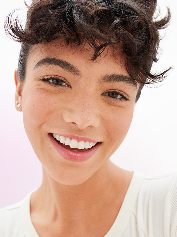 Ein weibliches Model mit nat&uuml;rlichem Make-up blickt in die Kamera.