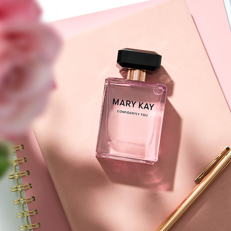 Ein Flacon Mary Kay Confidently You Eau de Parfum - von oben fotografiert, in einem Setting mit rosa Notizbuch, Stift und einer Rose