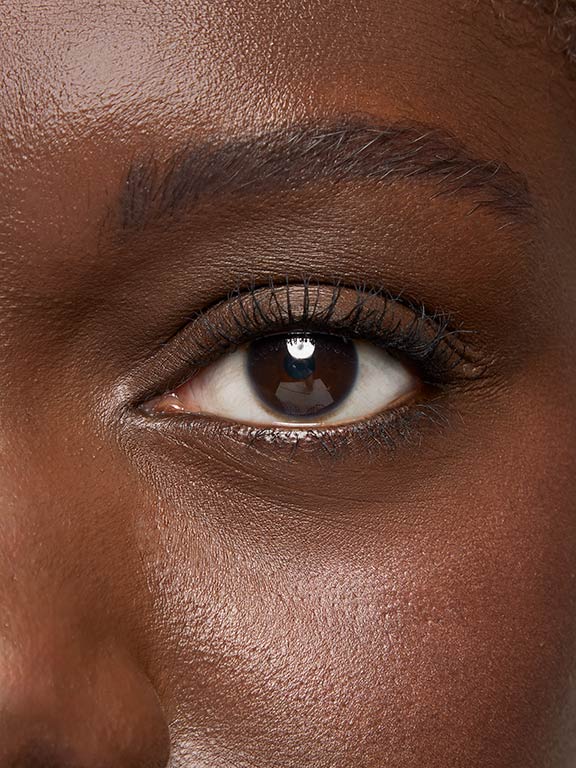 Das Auge einer Frau mit dunklem Hauttyp, nachdem sie die Mary Kay Great Hights Wimperntushe aufgetragen hat