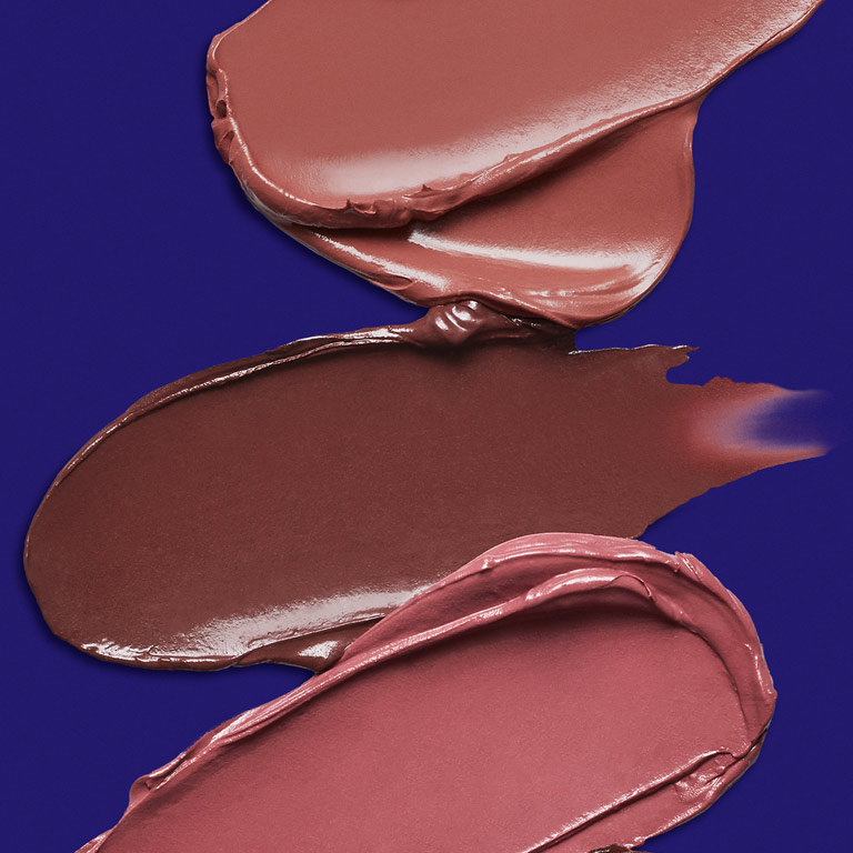 Abdr&uuml;cke von drei nudefarbenen Lippenstiften (Mary Kay Supreme Hydrating Lipsticks) auf einem dunkelblauen Hintergrund