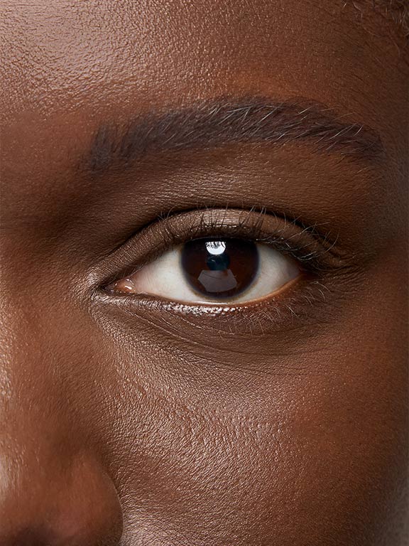 Das Auge einer Frau mit dunklem Hauttyp, bevor sie Wimperntusche aufgetragen hat