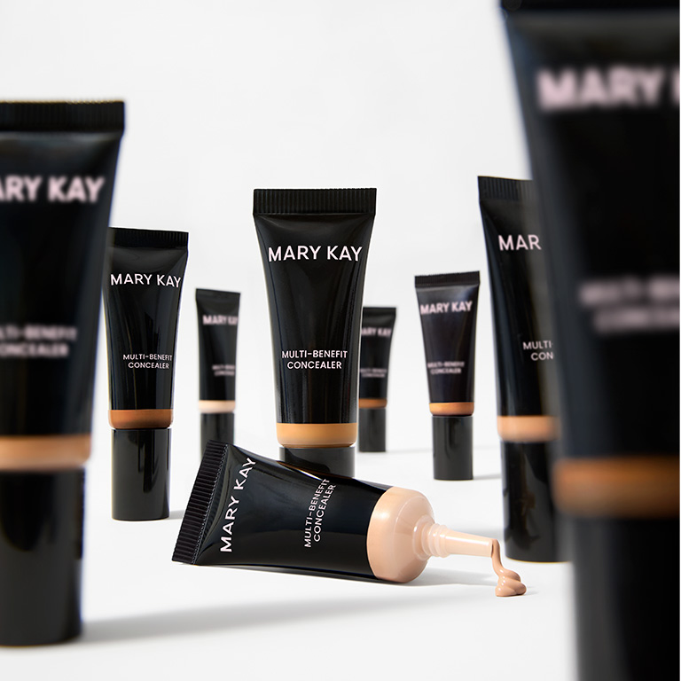 Einige Tuben Mary Kay Multi-Benefit Concealer in unterschiedlichen Farbnuancen stehen aufrecht. Eine Tube liegt und es kommt Concealer heraus (in einem hellen Farbton).