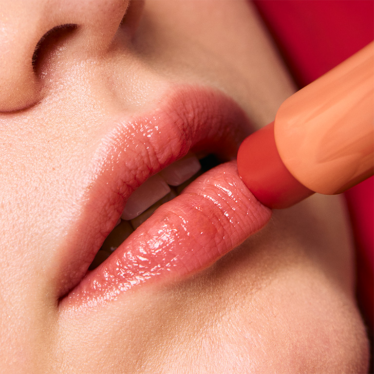 Model beim Auftragen des limitierten Mary Kay Tinted Lip Balm in Coral Blaze