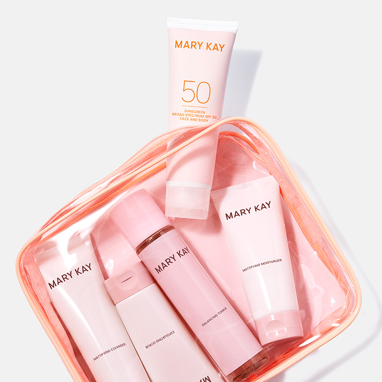 In einer durchsichtigen, rosa Kosmetiktasche sieht man das Mary Kay Skin Care Mattifying Basis-Set (Toner, Cleanser, Moisturizer und Scrub) sowie die Mary Kay Sonnencreme f&uuml;r Gesicht und K&ouml;rper (LSF 50+)