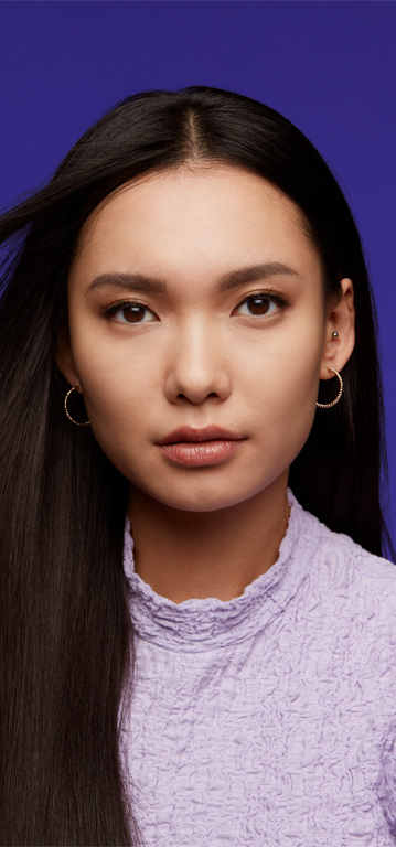 Eine Frau mit dunklem Haar und hellem Hauttyp tr&auml;gt den Mary Kay Supreme Hydrating Lipstick in einem hellen Nudeton (Hushed Blush) und l&auml;chelt in die Kamera