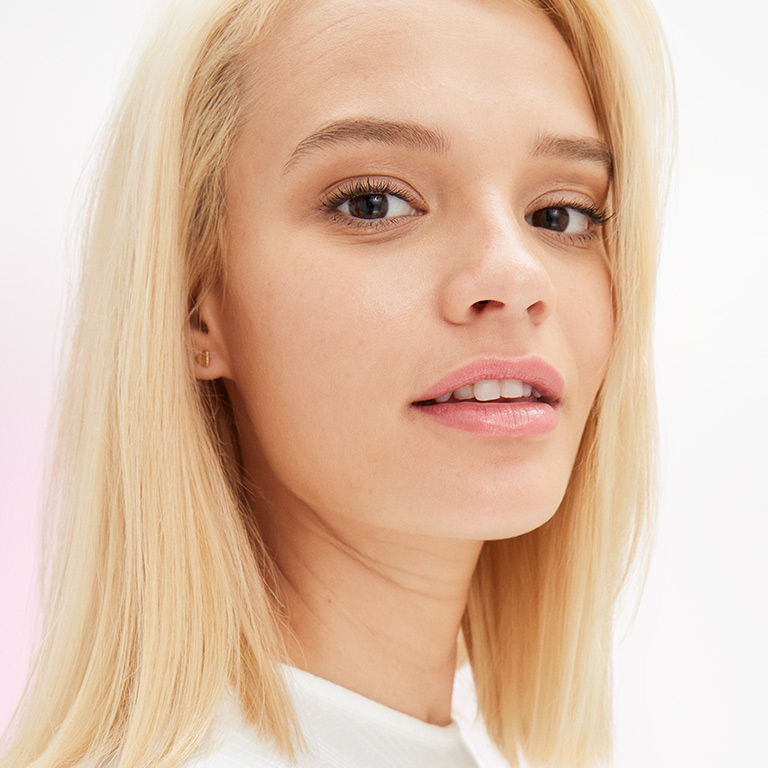Ein weibliches Model mit nat&uuml;rlichem Make-up blickt in die Kamera.