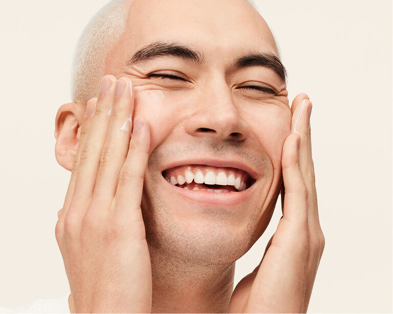 Nahaufnahme eines Mannes, der die Augen geschlossen hat und mit beiden H&auml;nden ein MK Men Gesichtspflegeprodukt im Gesicht verteilt (MK Men Ultimate Moisturizer - eine pflegende Gesichtscreme)