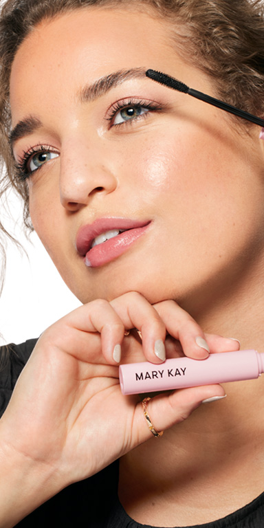 Eine Frau h&auml;lt in der einen Hand die rosa Tube der Mary Kay Great Heights Mascara und tuscht mit der anderen Hand ihre Wimpern
